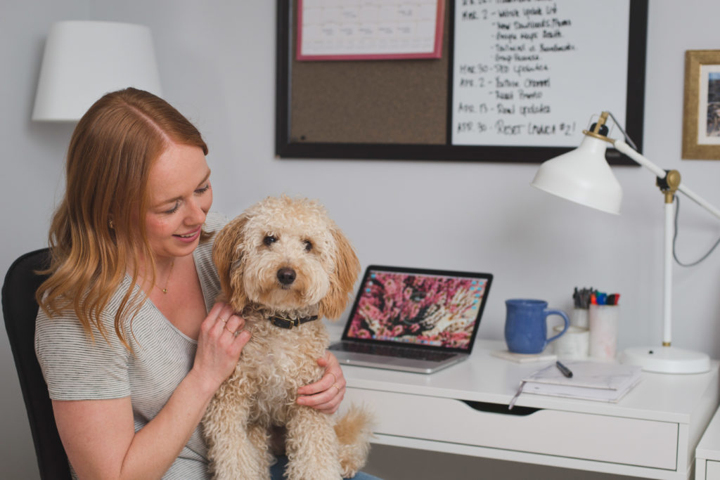 Stephanie Kay cuddling with her dog Arthur at her desk