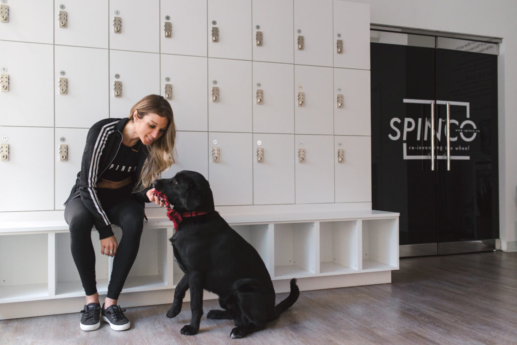 spin instructor cuddling with her black lab outside of spin studio