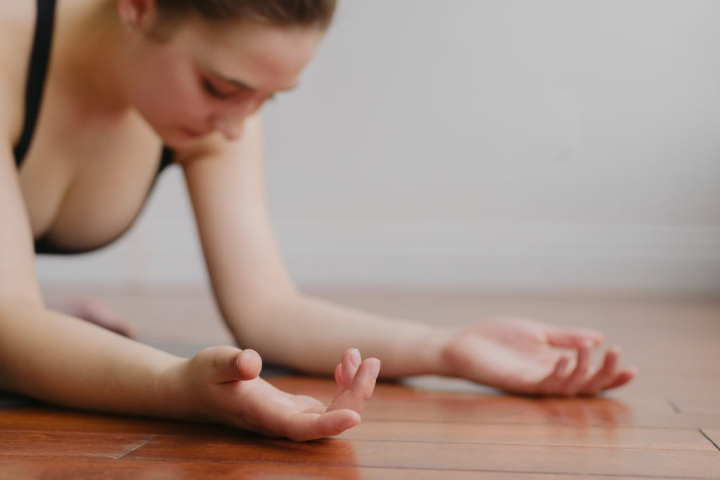 yoga teacher surrendering in pigeon pose with palms facing up