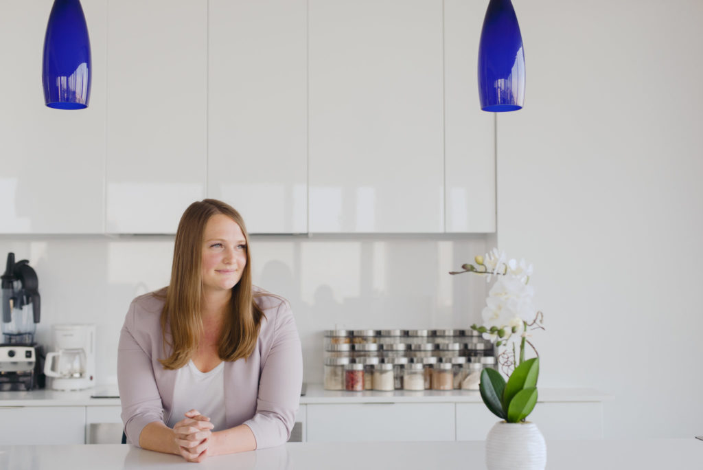real estate agent leaning against white countertop in kitchen looking out the window