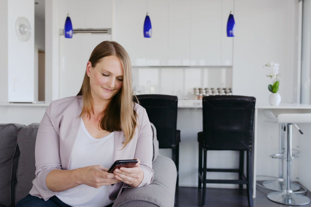 real estate agent sitting on the couch working from her cellphone