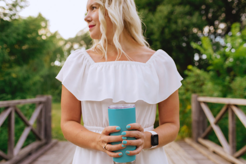 ottawa content marketing specialist holding a blue coffee mug on a wooden bridge