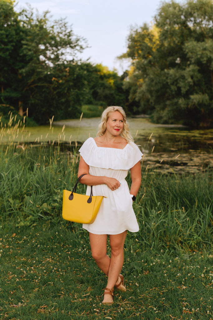 content marketing specialist standing by a pond at sunset with yellow purse