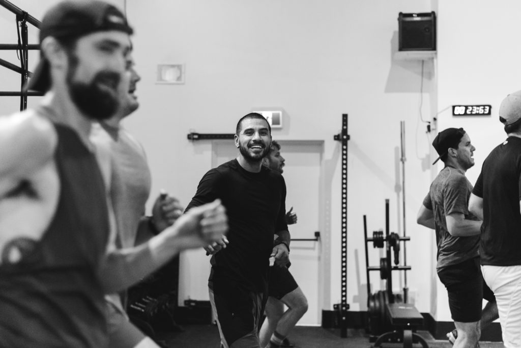 personal trainer smiling as men workout
