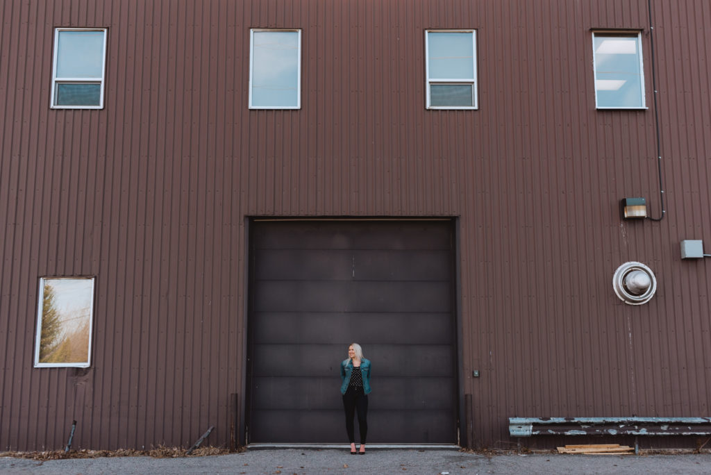 girl standing in front of industrial building wearing a jean jacket