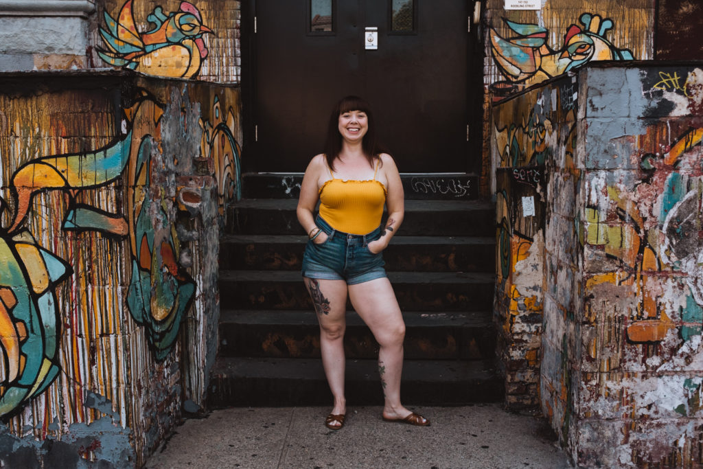 Megan in yellow tank on graffiti wall