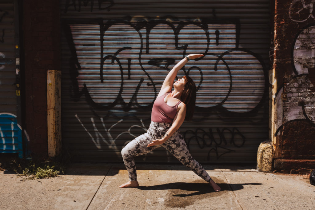 yoga teacher in reverse warrior against graffiti wall