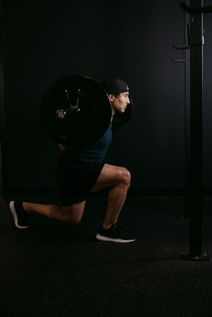 Andre Signoretti doing a reverse lunge with a barbell