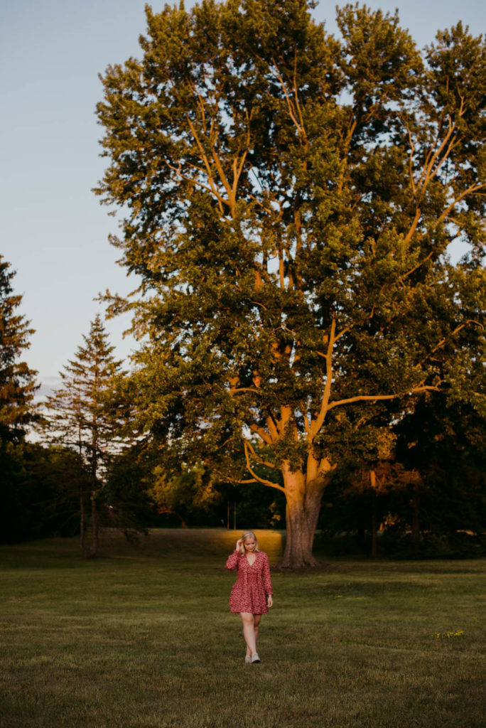 girl in a red dress walking in a field at sunset