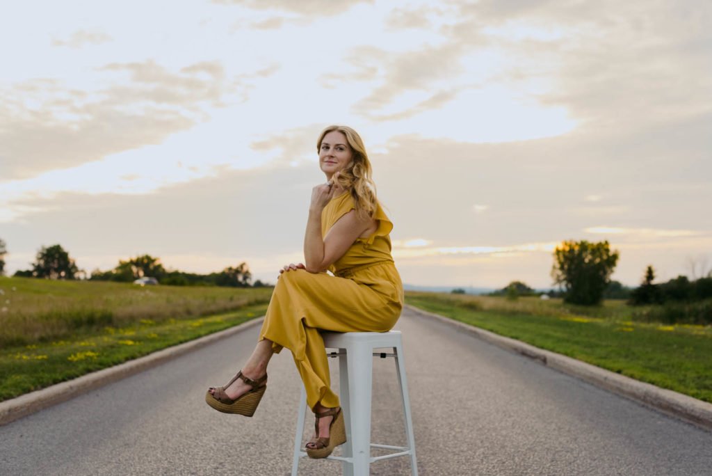 Stephanie Karlovits sitting on a stool in the middle of a road at sunset