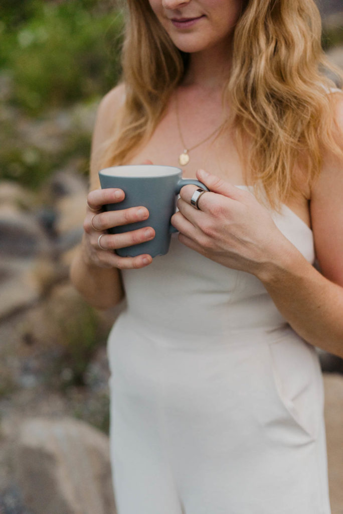 Stephanie Karlovits female entrepreneur wearing a white jumper holding a coffee mug outdoors