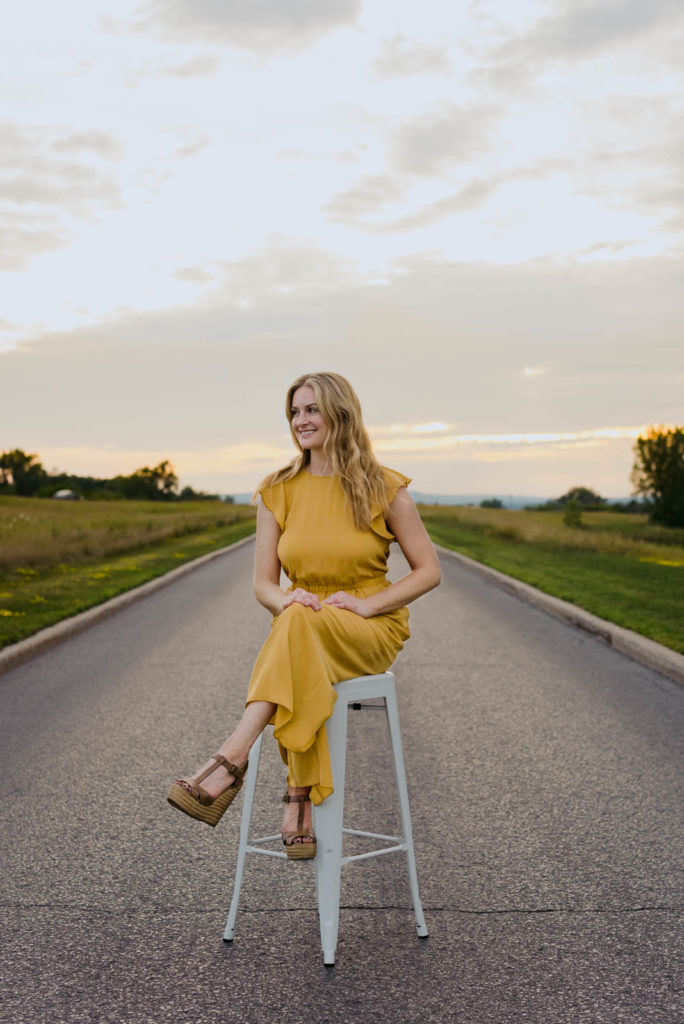 Stephanie Karlovits sitting on a stool in the middle of a road at sunset