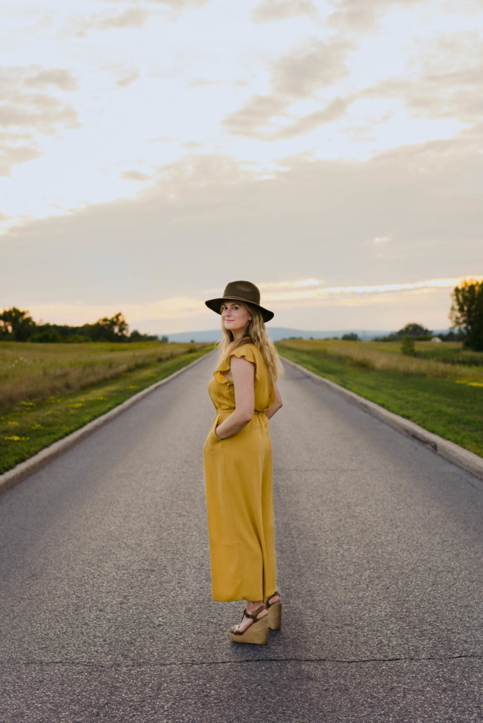 Stephanie Karlovits wearing a hat standing in the middle of a road at sunset