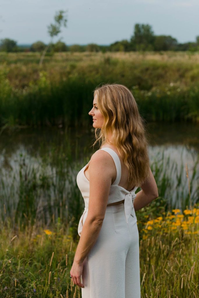 Stephanie Karlovits female entrepreneur wearing a white jumper by a pond at sunset