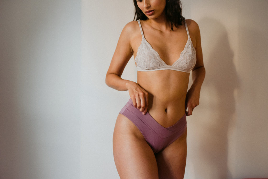 indie lingerie model wearing bralette and mauve pulling up mauve underwear
