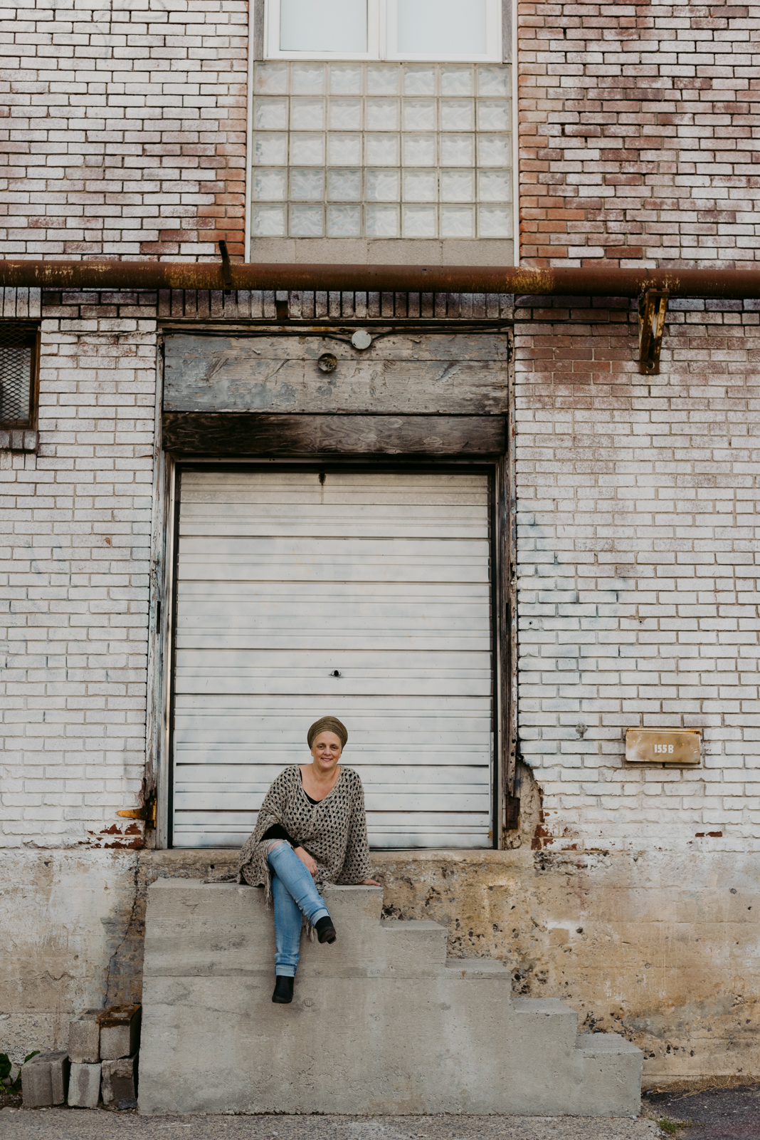 lifestyle photo of yoga teacher sitting on old loading dock steps of an old brick building