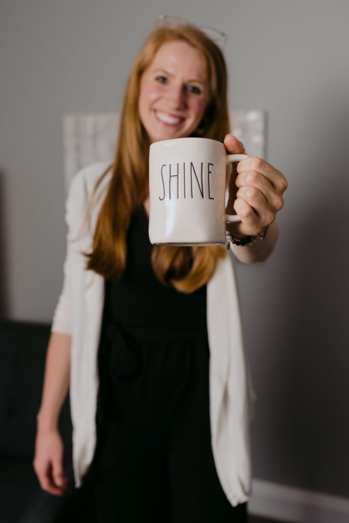 Therapist Tesia Bryski holding a coffee mug that says "shine"