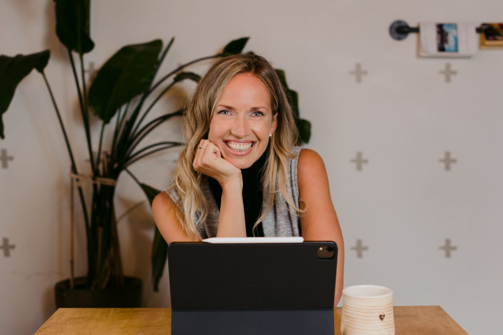 female business owner smiling at the camera working at a table with a mug of tea
