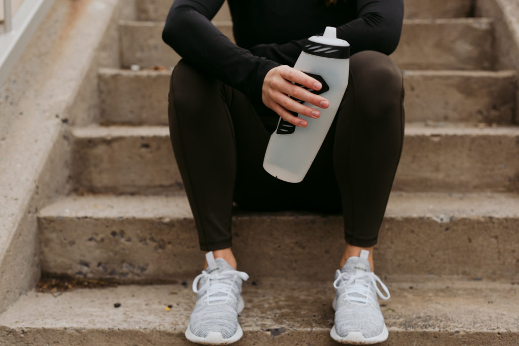 physiotherapist holding water bottle sitting on a staircase