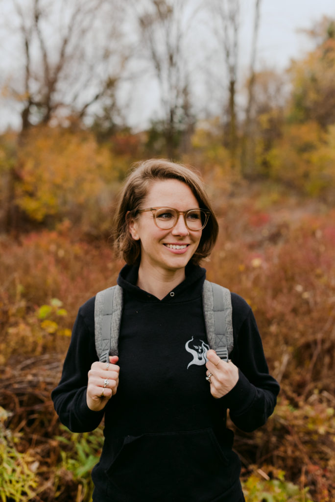 copywriter wearing a backpack trekking through the woods in the fall