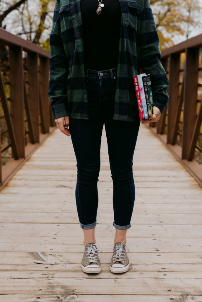 copywriter holding books against her hip standing on a bridge