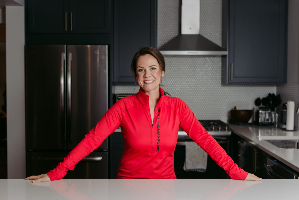 woman standing at the kitchen counter wearing pink smiling at the camera