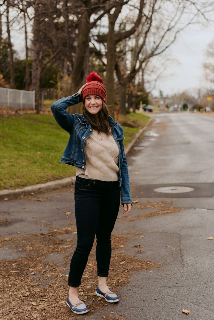 woman in a jean jacket and red touque on the street