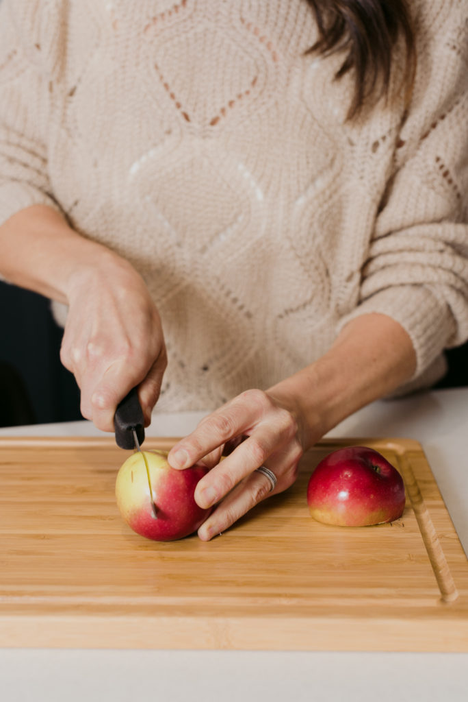 woman cutting up an apple on a wooden cutting board