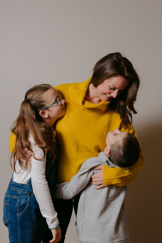 mom wearing yellow sweater hugging her kids