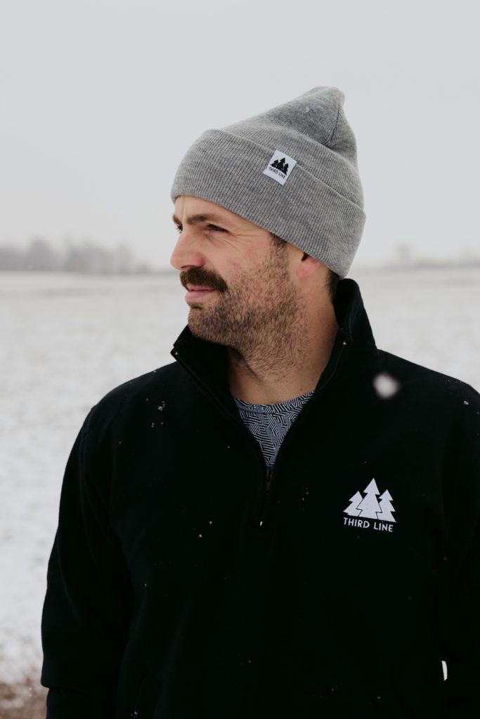 man wearing a grey toque in the middle of snowy field