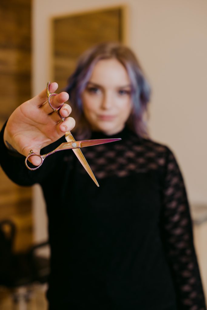 hair stylist holding a pair of purple scissors