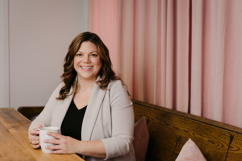 Real estate agent Daria Kark sitting at wooden table drinking coffee