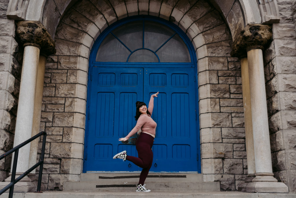 yoga teacher dancing in front of blue church door