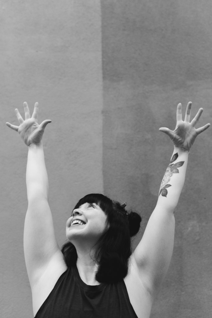 ottawa yoga teacher with arm up overhead smiling in black and white