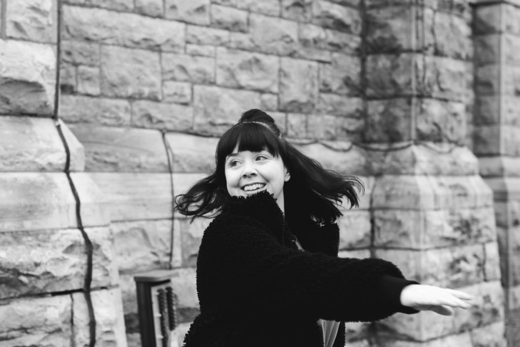 ottawa yoga teacher dancing in front of stone church in black and white