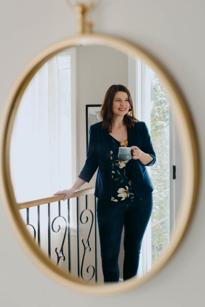 female entrepreneur reflected in a window holding a coffee cup