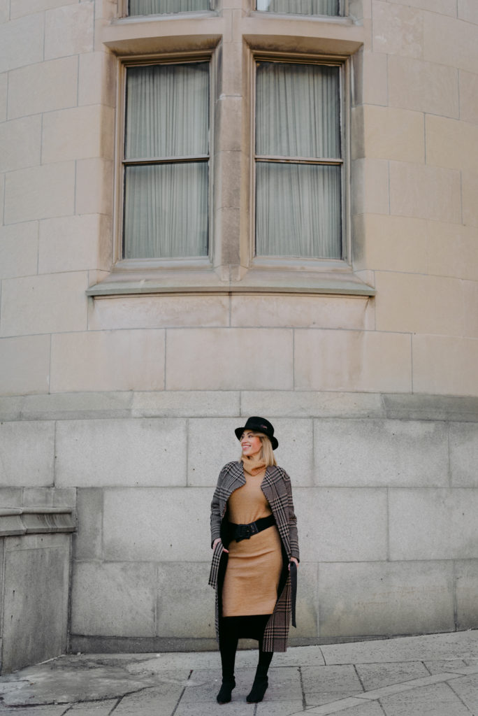 Woman wearing black hat and wool coat in front of stone building