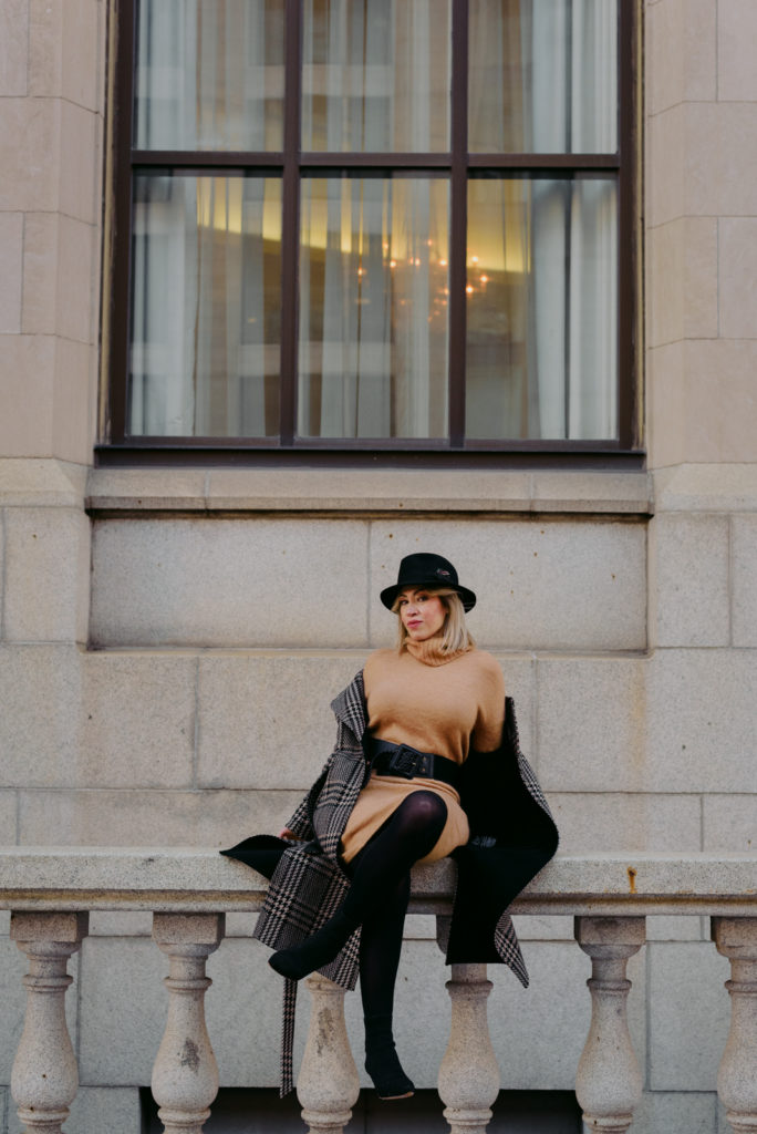 Woman wearing black hat sitting on stone railing