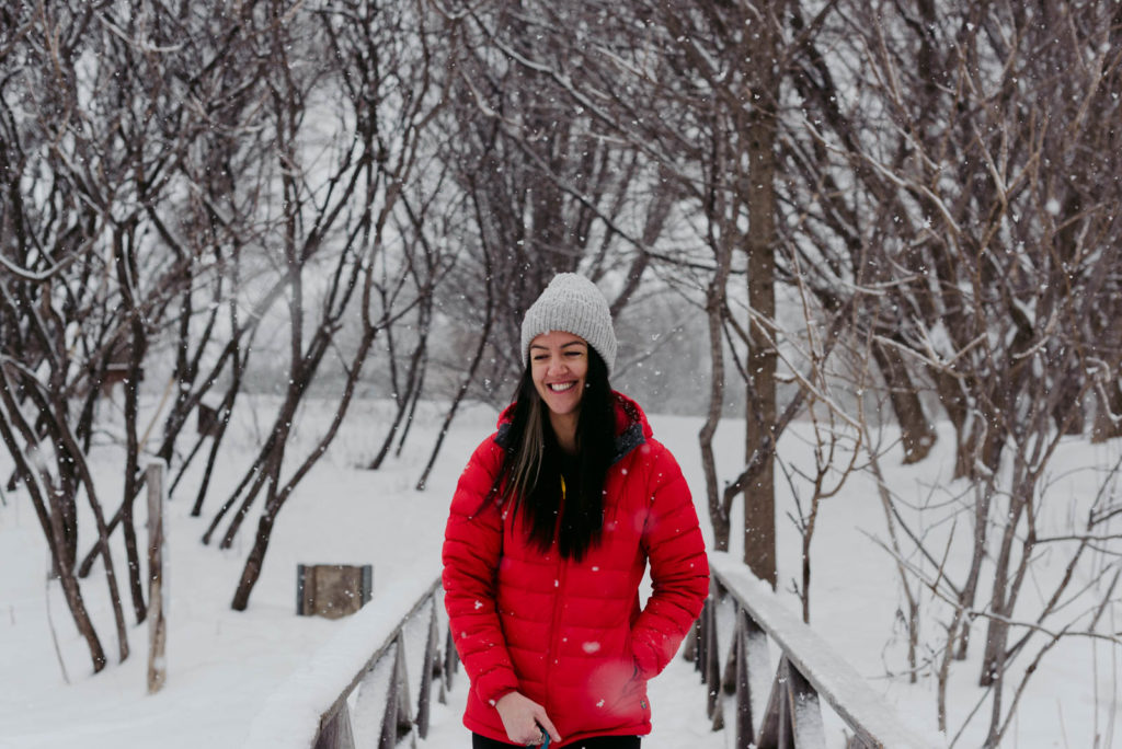 female entrepreneur walking on a wooden bridge in the snow wearing a red jacket