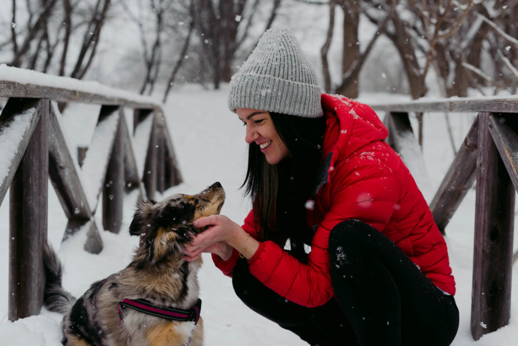 female entrepreneur walking her dog in the snow on a wooden bridge
