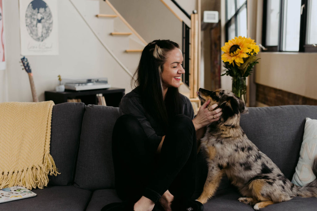 female entrepreneur sitting on her couch with her dog