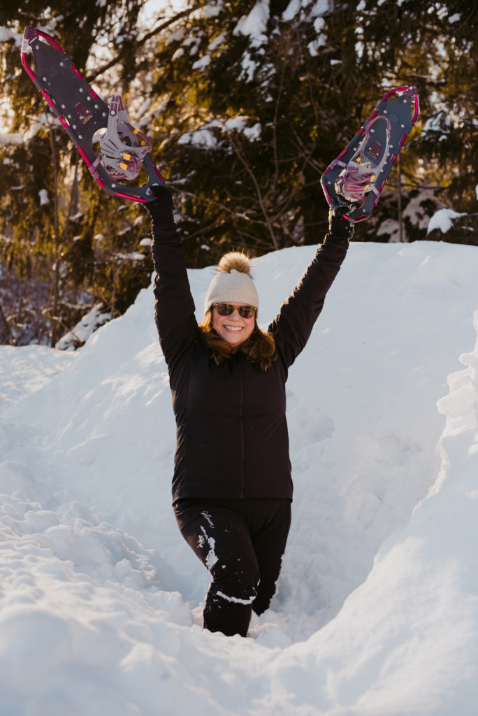 real estate agent holding up her pink snowshoes in gatineau park