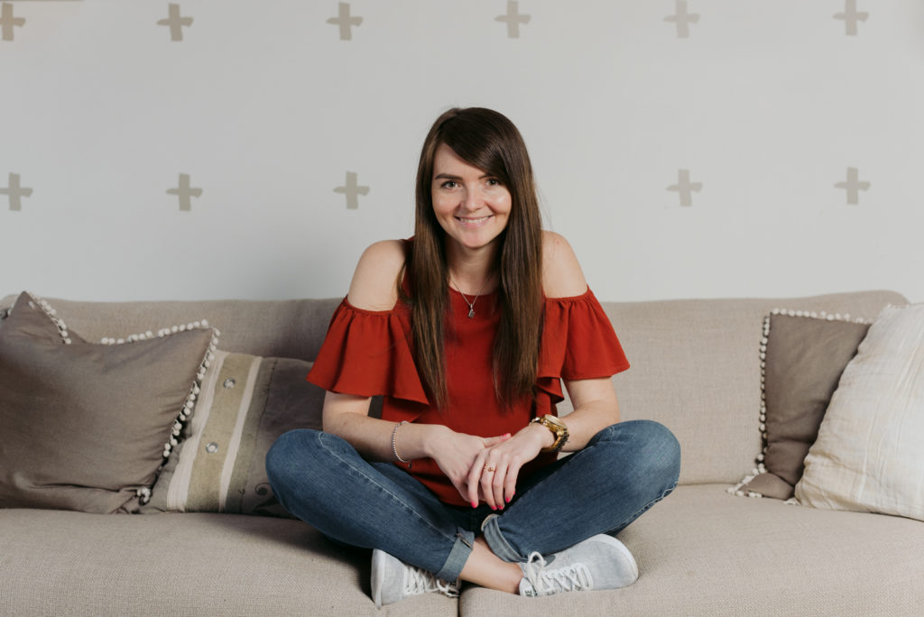 woman sitting cross legged on couch smiling at the camera