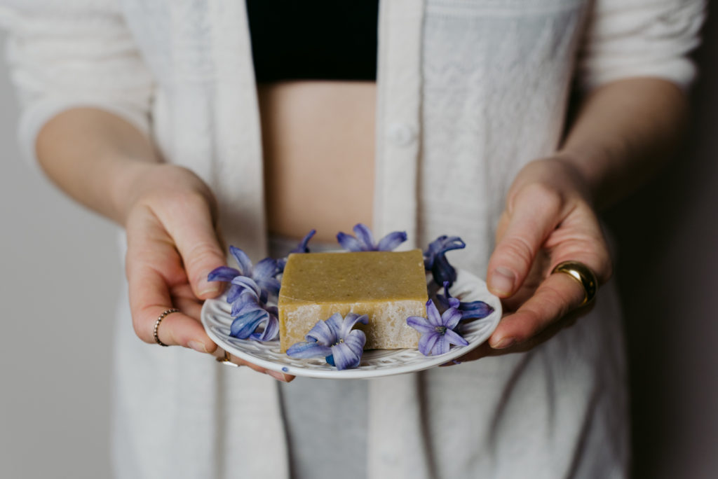 woman holding CBD infused soap dish with purple flowers