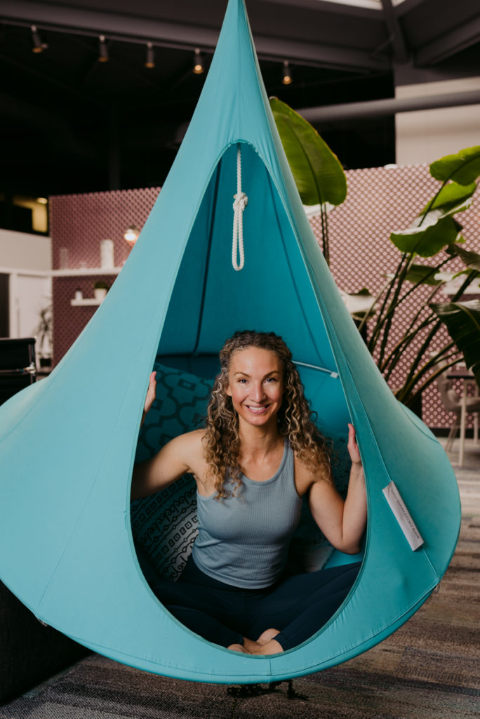 yoga teacher sitting in blue hanging hammock chair