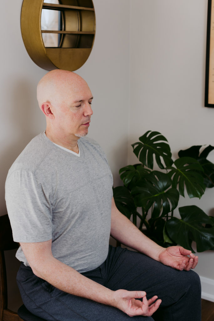 yoga teacher sitting on a chair meditating