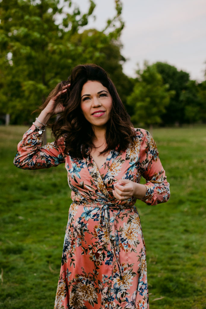 woman wearing a floral dress in a park at sunset