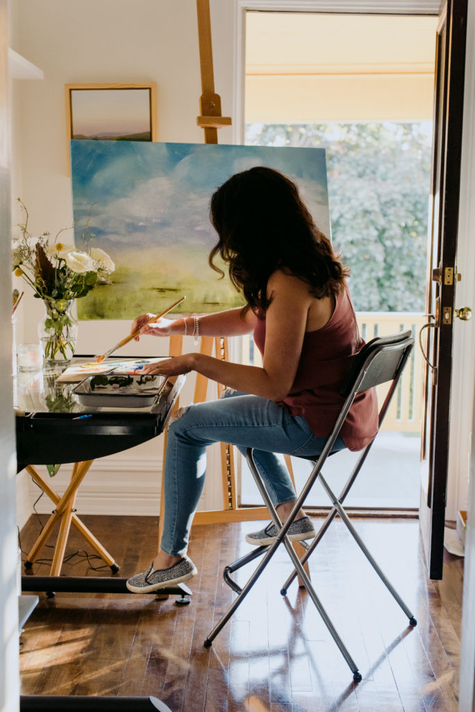 woman sitting at easel in her studio painting