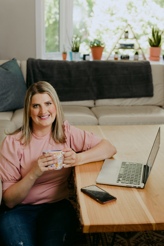 virtual assistant sitting on floor next to coffee table with laptop and coffee
