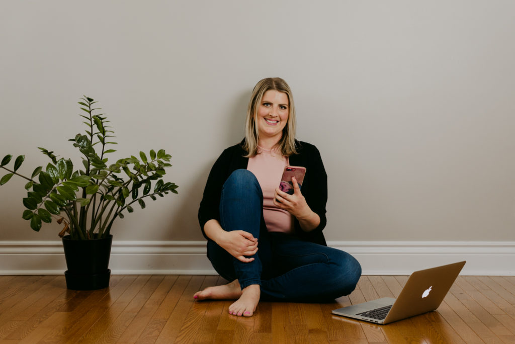 virtual assistant sitting on the floor next to plant with laptop